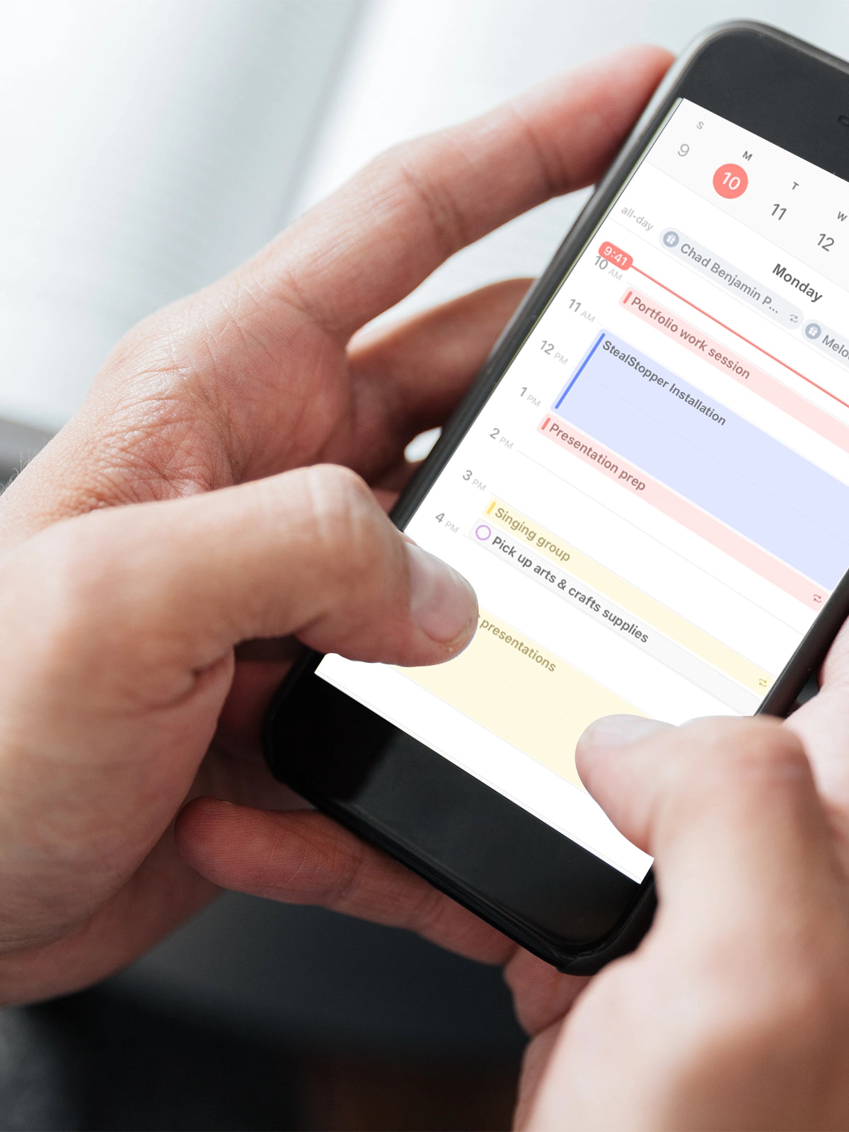 Person using a smartphone with a calendar app displayed on the screen.